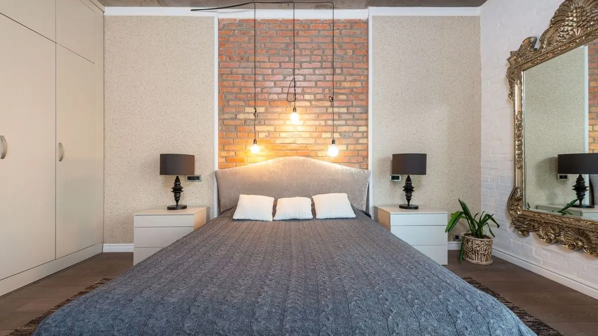 Contemporary bedroom with a brick accent wall, fitted wardrobe and pendant lights