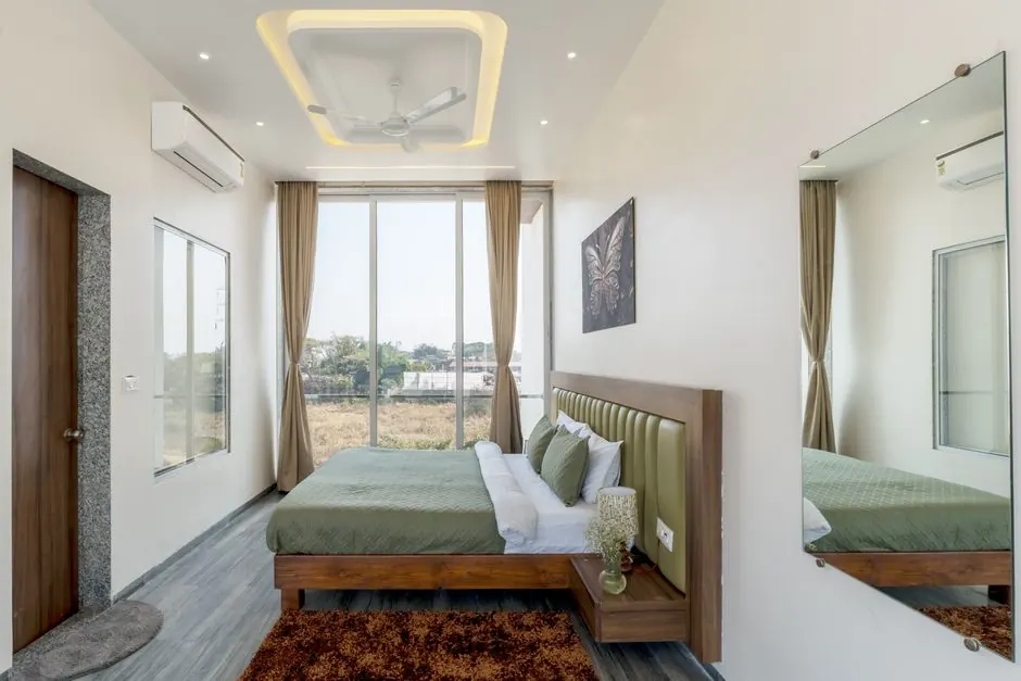 Bedroom with a gypsum false ceiling cove, wall-mounted air conditioner and upholstered headboard