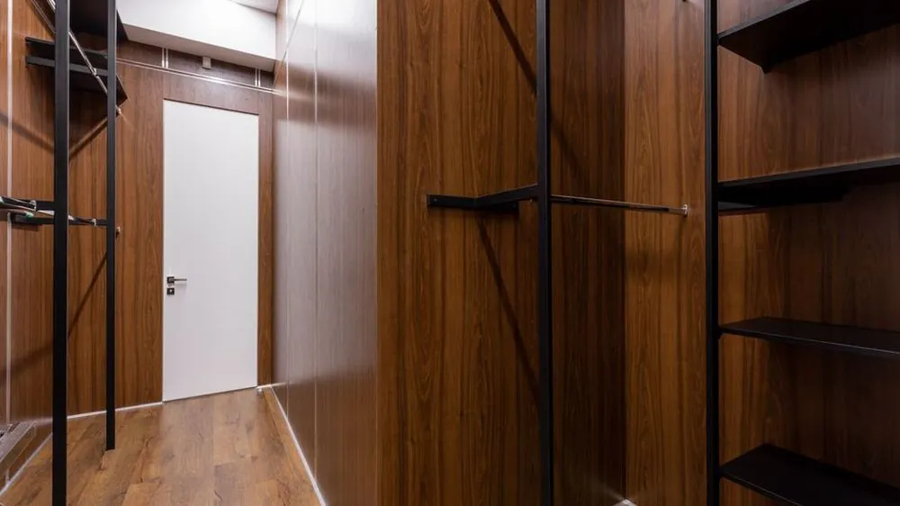 Walk-in wardrobe lined with wood-grain panels, hanging rails and open shelves