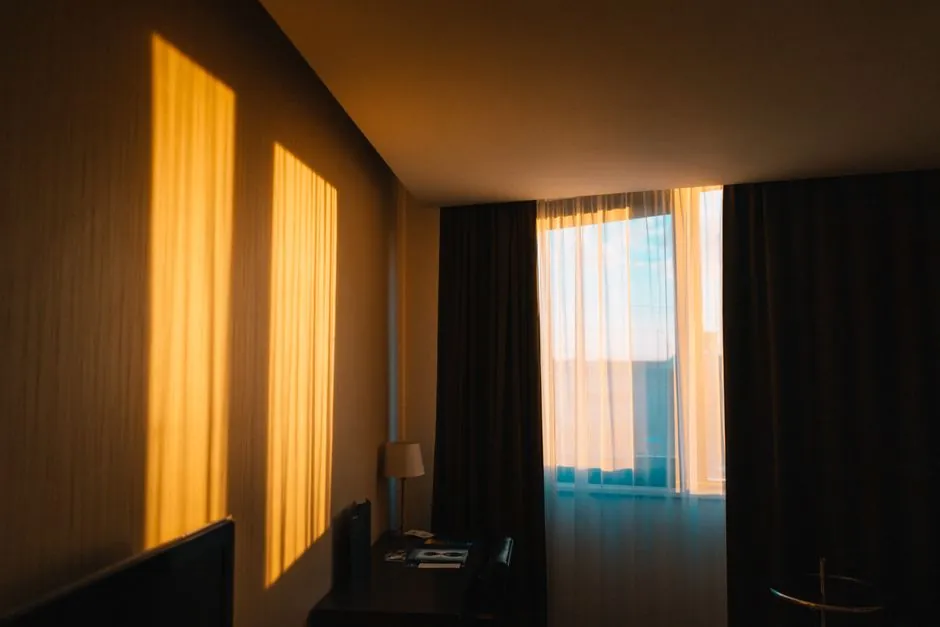 Sheer and dark dim-out curtains layered at a sunlit window