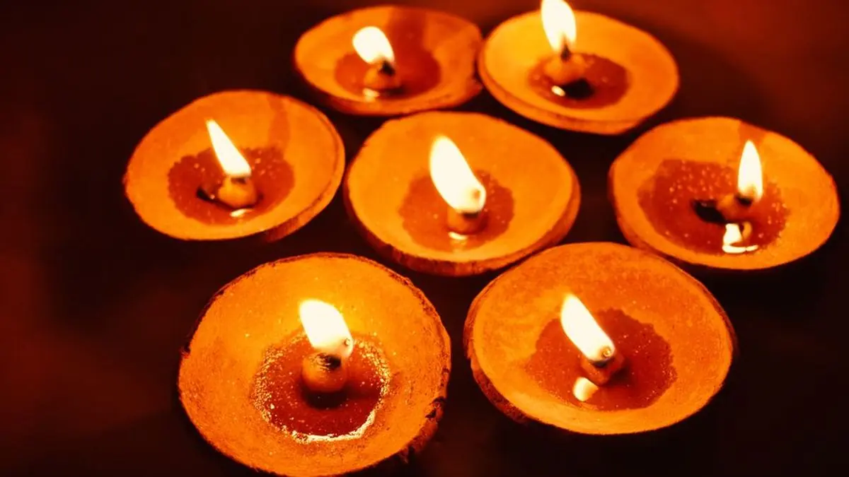 Row of lit clay diyas glowing warm orange for Diwali decoration