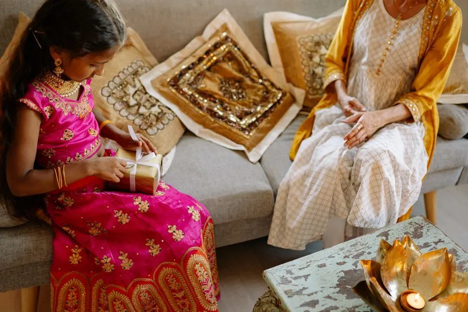 Living room sofa with festive cushions and a brass lotus tea light on a table during Diwali