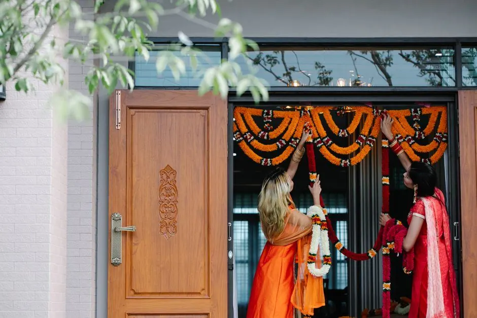 Marigold and red flower garlands hung over a wooden front door for Diwali