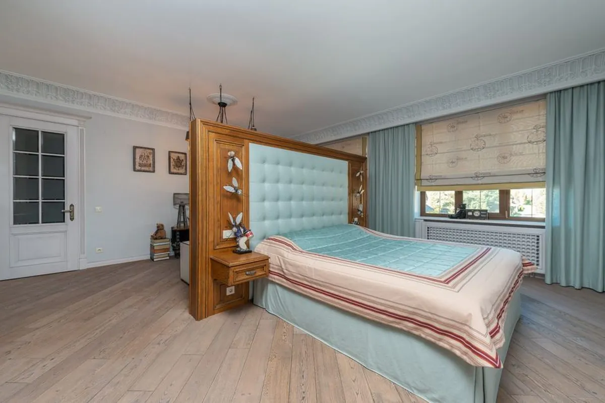 Wide plank wooden flooring in a bedroom with a cushioned headboard
