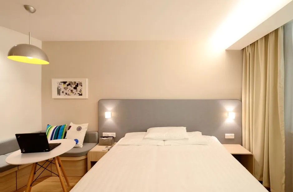 Bedroom with a round table and laptop beside the bed used as a compact work corner