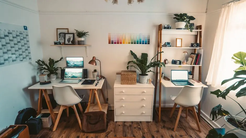 Two desks and open shelves forming a shared home workspace with a chest of drawers