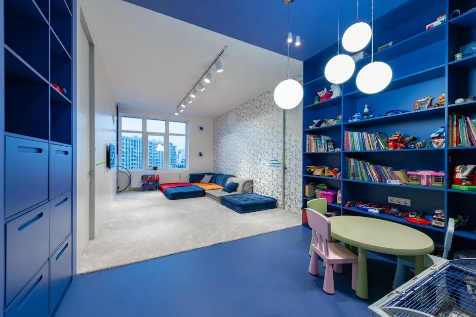Playroom with blue open shelves, floor cushions and a small table