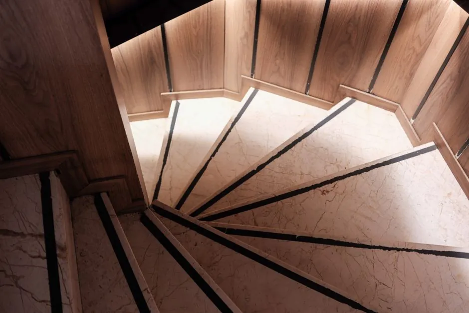 Wide timber staircase with slim metal balustrade and continuous handrail in a bright hall