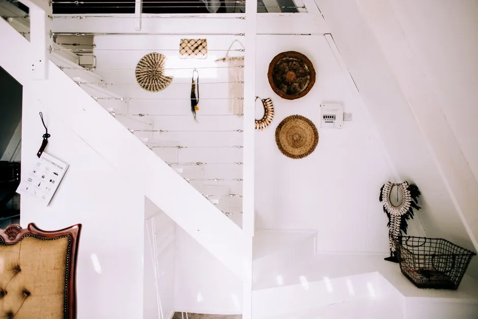 White staircase with cable railing and wall display in the space beside and under the flight