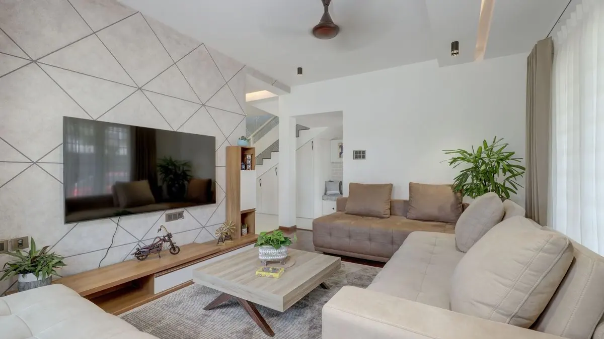 Spacious living room with a wall-mounted TV on a patterned feature wall and a low wooden unit