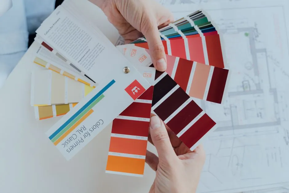 Hand holding paint colour swatch fans over a floor plan